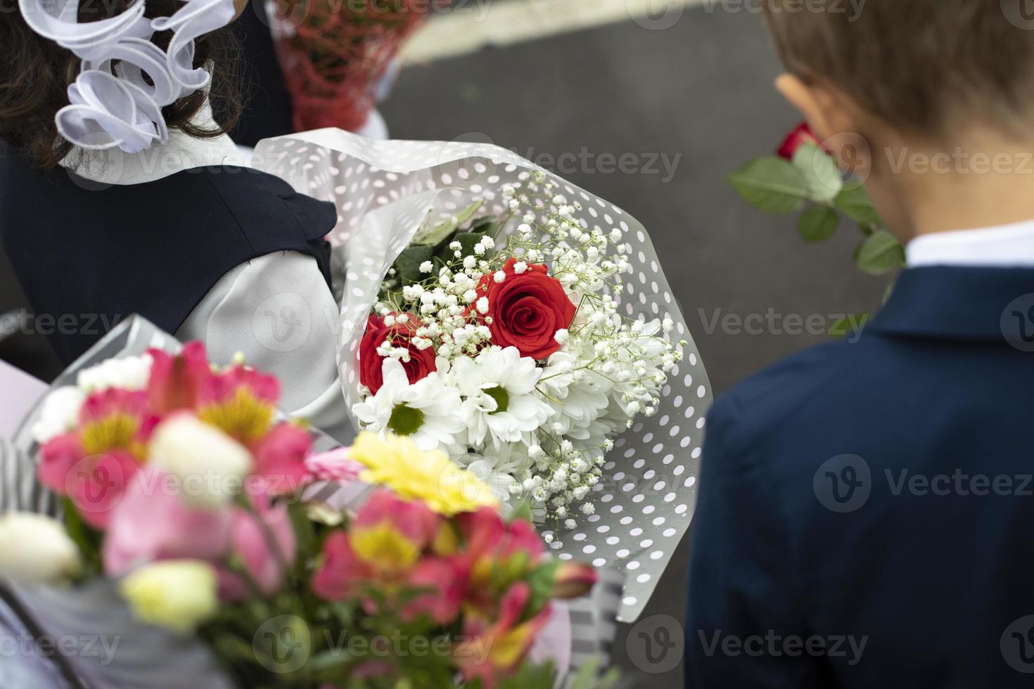 Flowers in hands of child. Bouquet of flowers for teacher. Details of holiday at school. School day. photo