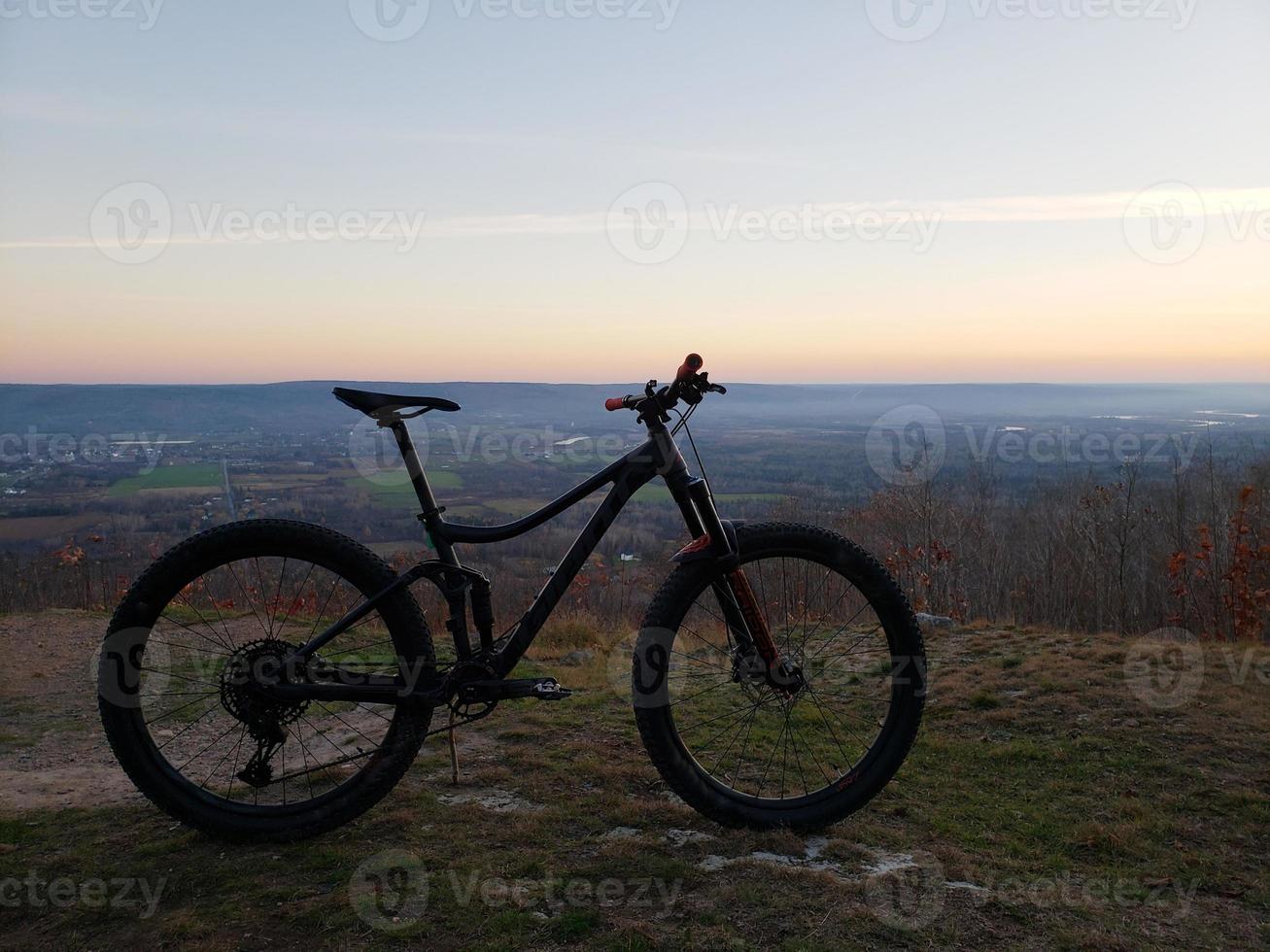 A mountain bike silhouetted with a sunset and farm land background photo