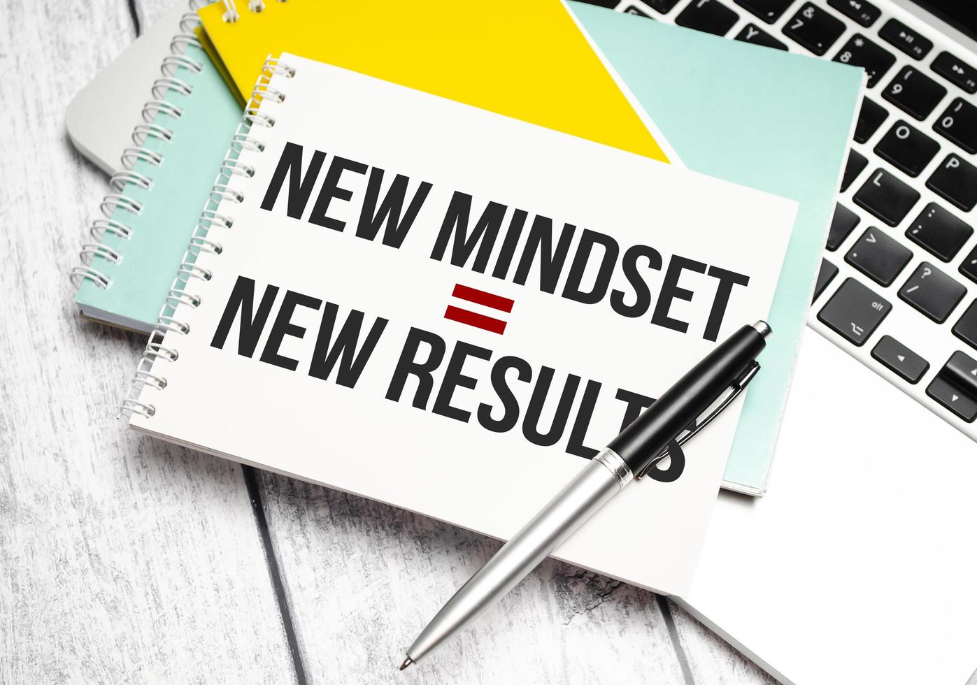 New Mindset - New Results words on yellow notebook and pen, charts and laptop photo