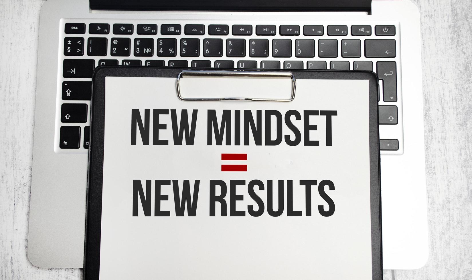 New Mindset - New Results words on yellow notebook and pen, charts and laptop photo