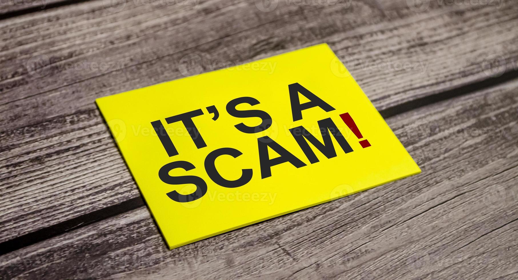 it is a scam word on yellow sticker and wooden background photo