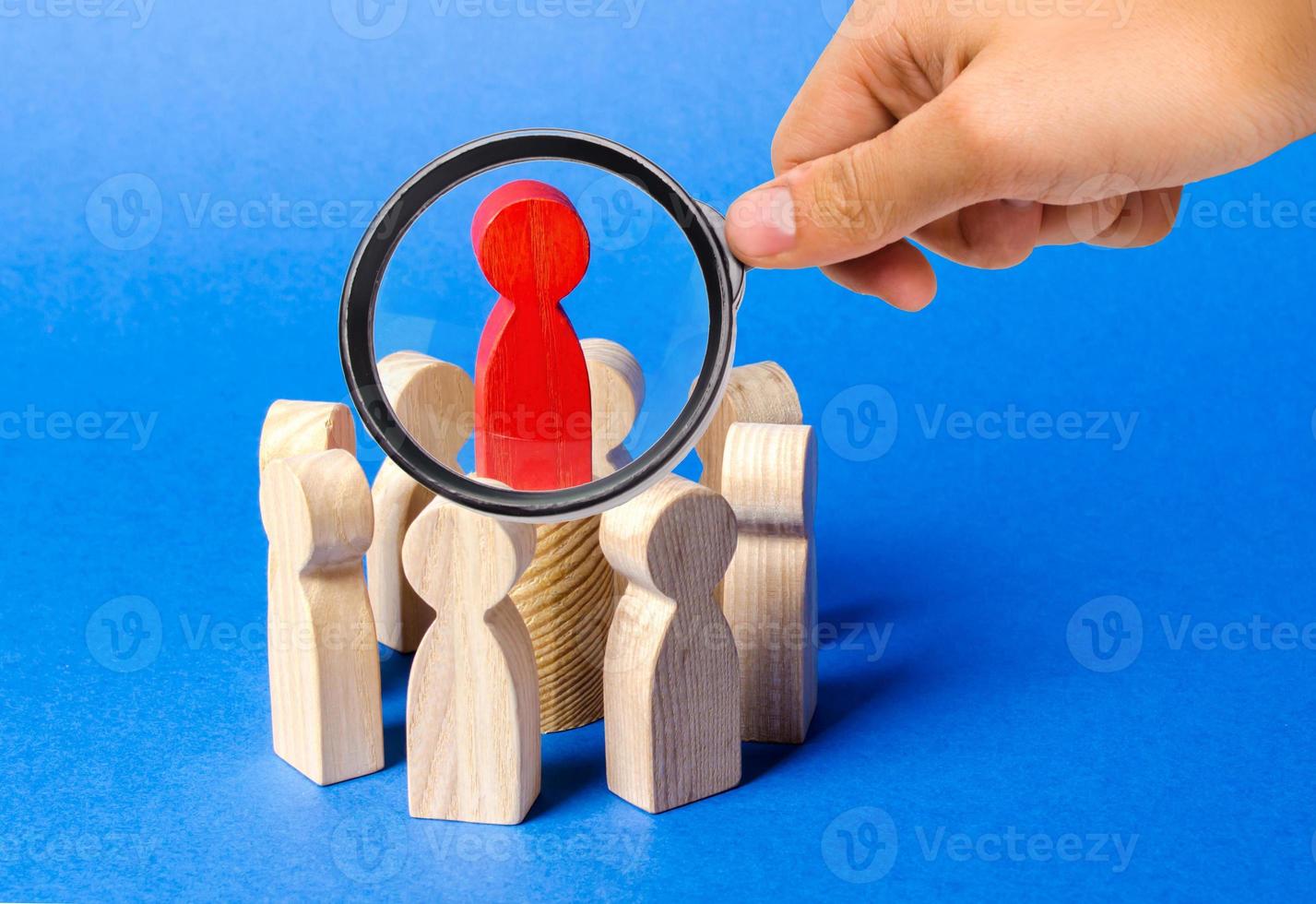 A magnifying glass looks at a red figure of the leader in the center of the circle of people. Creating a business team and its management. Cooperation and collaboration. Fundraising photo