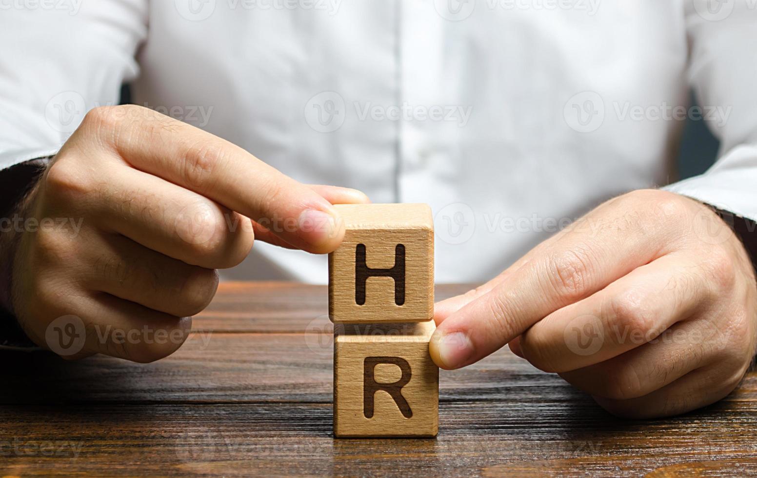 Businessman holds two blocks with letters HR. Recruiting new workers, headhunters Human resources. Attraction personnel to the company. Search for talented worker. Assessment of qualities skills. photo