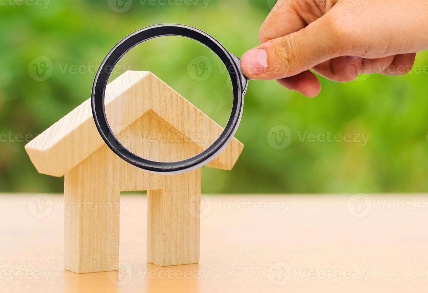 A magnifying glass looks at a wooden house. The concept of buying and selling real estate, renting. Search for a house. Affordable housing, credit and loans. Investments photo