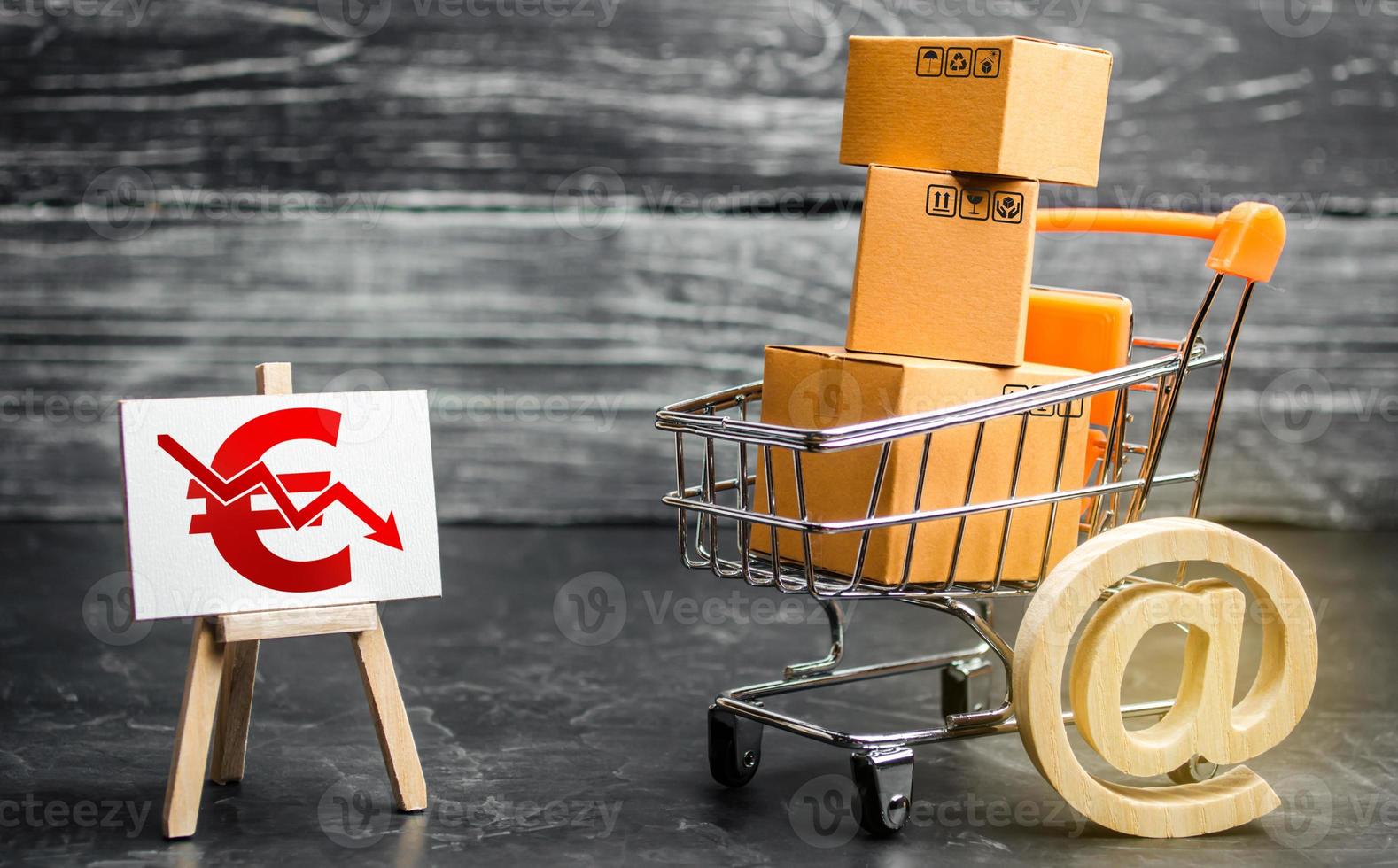 Shopping cart loaded with boxes, email symbol and euro red down arrow. Reduced online sales over Internet. Fall purchasing power. Price reduction. High competition. Low profits return on investment photo