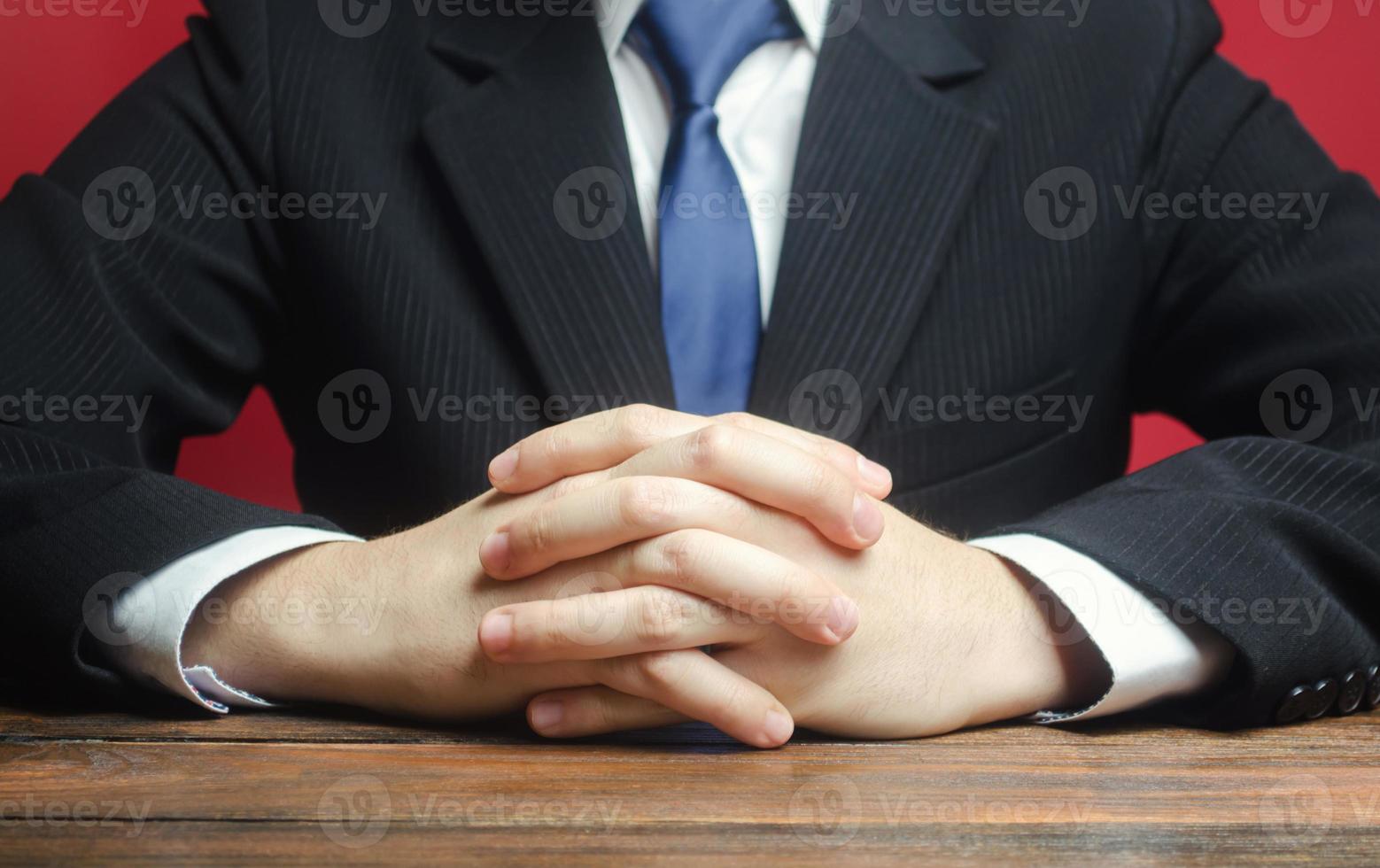 un hombre se sienta a la mesa con los brazos cruzados. dispuesto a escuchar noticias y críticas. platica seria. tranquilamente. comunicación y expresiones corporales. entrevista de trabajo. tomar una decisión informada. humildad. foto