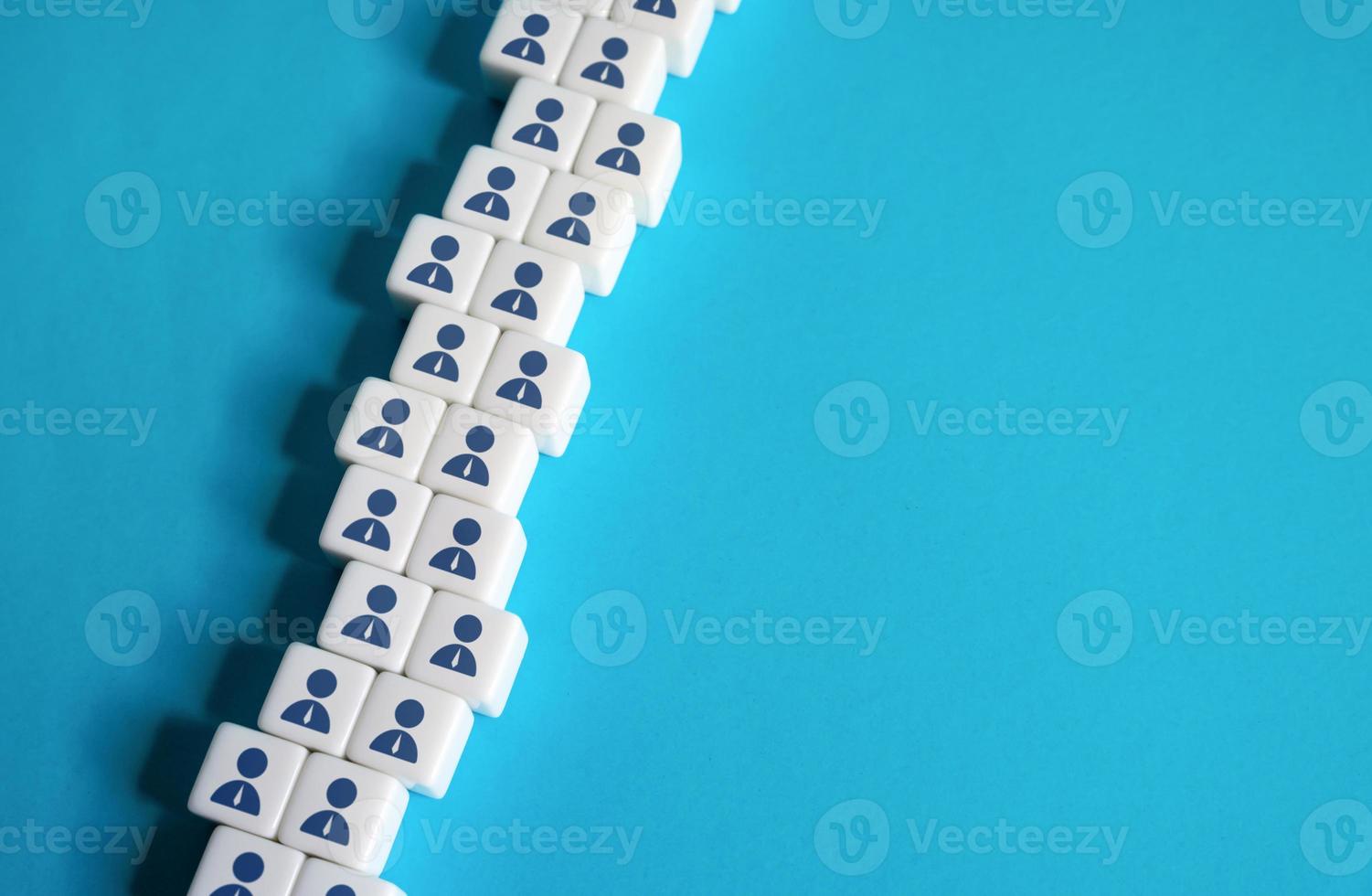 A chain of blocks of workers on a blue background. Place for text. Copyspace. Help wanted. Hiring new employees for vacancies. Human resources and work force. Staffing and recruiting candidates photo