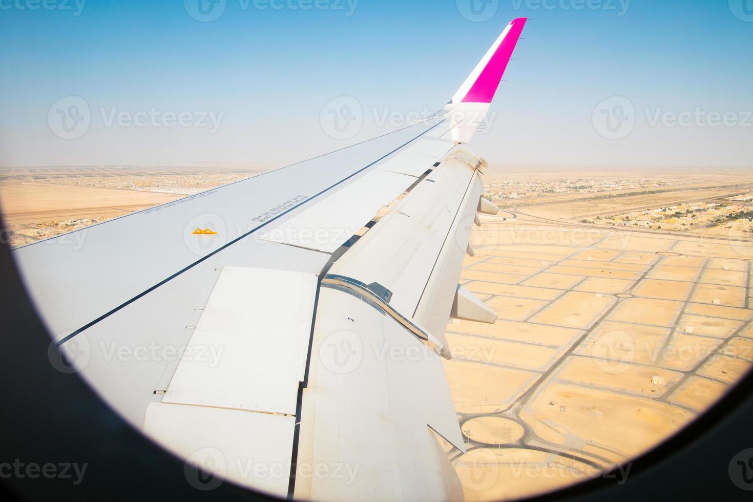 Aerial view over Abu dhabi city suburbs and desert with wing background window. Deserted landscape of UAE and plane wing view from cabin. Holidays vacation in middle east concept photo