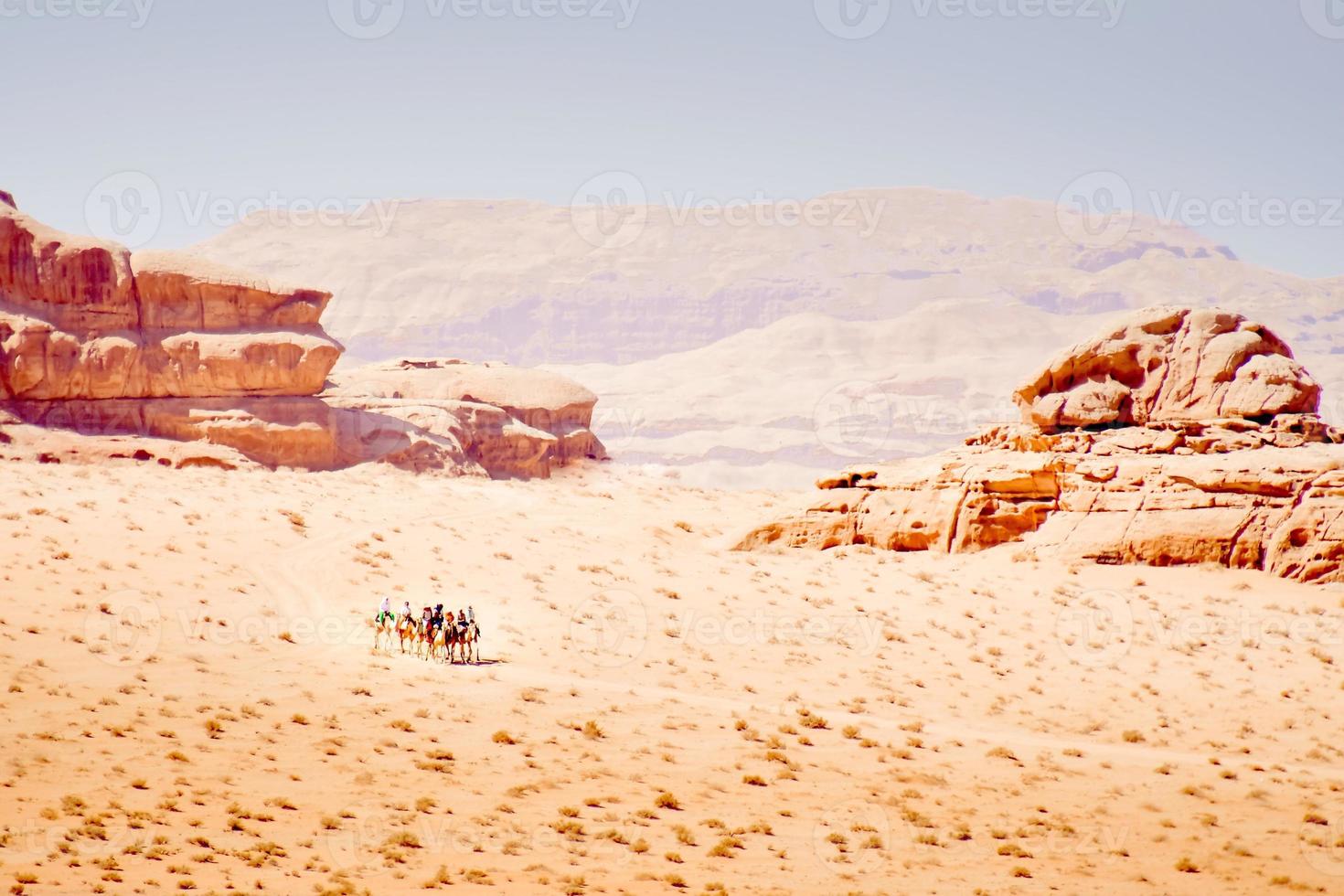 Group of tourist ride on camel caravan in wadi rum desert with scenic rock formations panorama photo