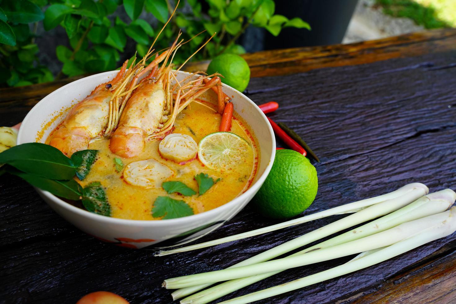 tom yum kung en una taza sobre un piso de madera, tom yum kung es también el plato nacional de tailandia. y es un alimento que es famoso en todo el mundo. foto