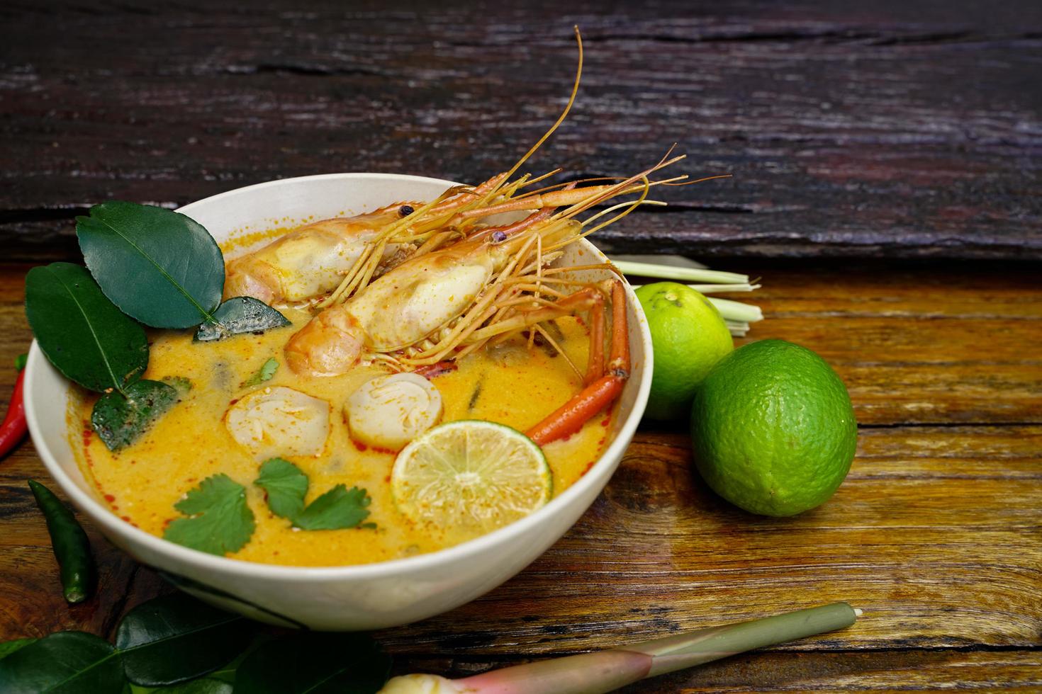 Tom yum kung in a cup on a wooden floor, Tom yum kung is also the national dish of Thailand.  And is a food that is famous all over the world. photo