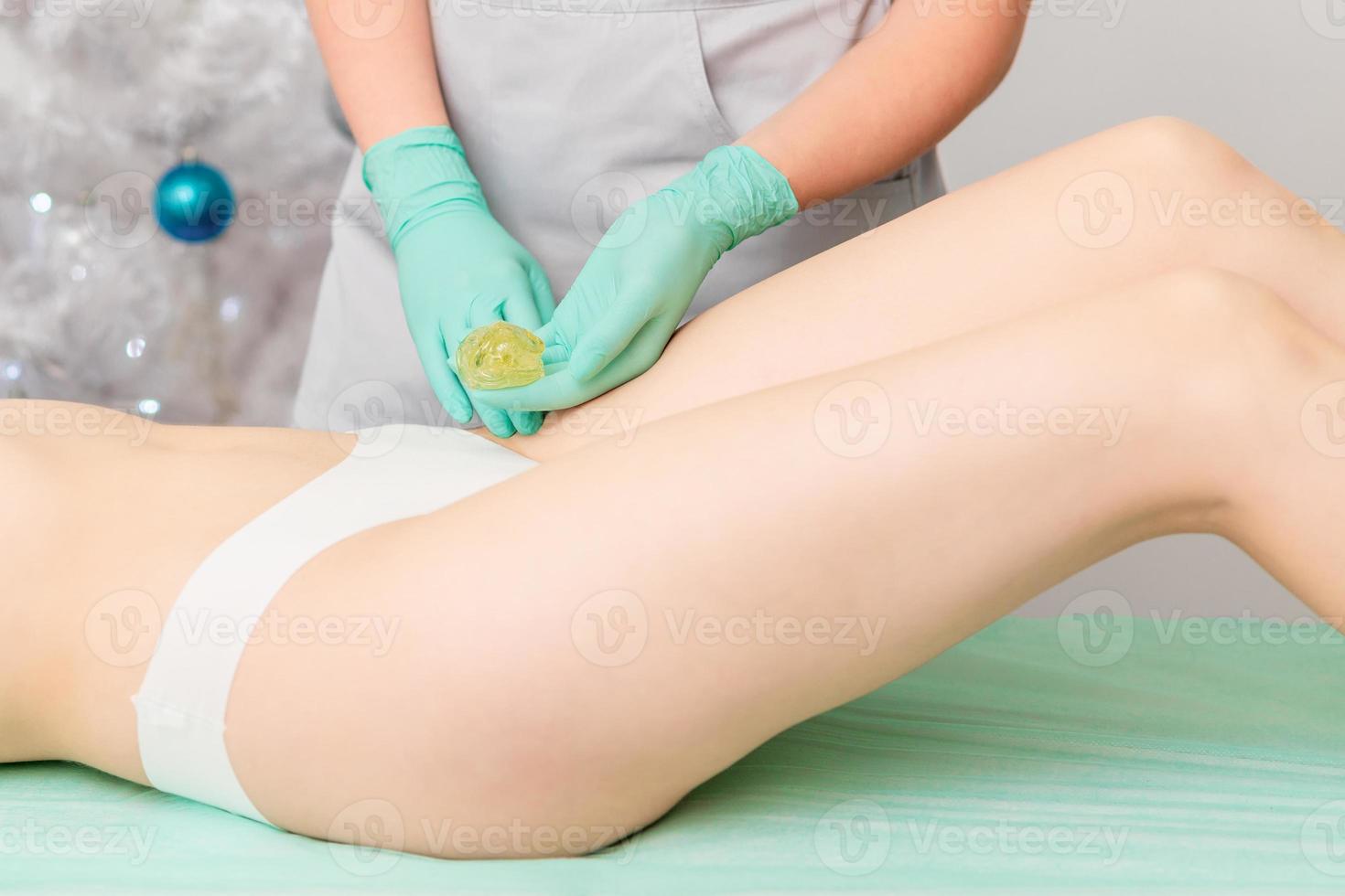 Beautician waxing legs of woman. photo