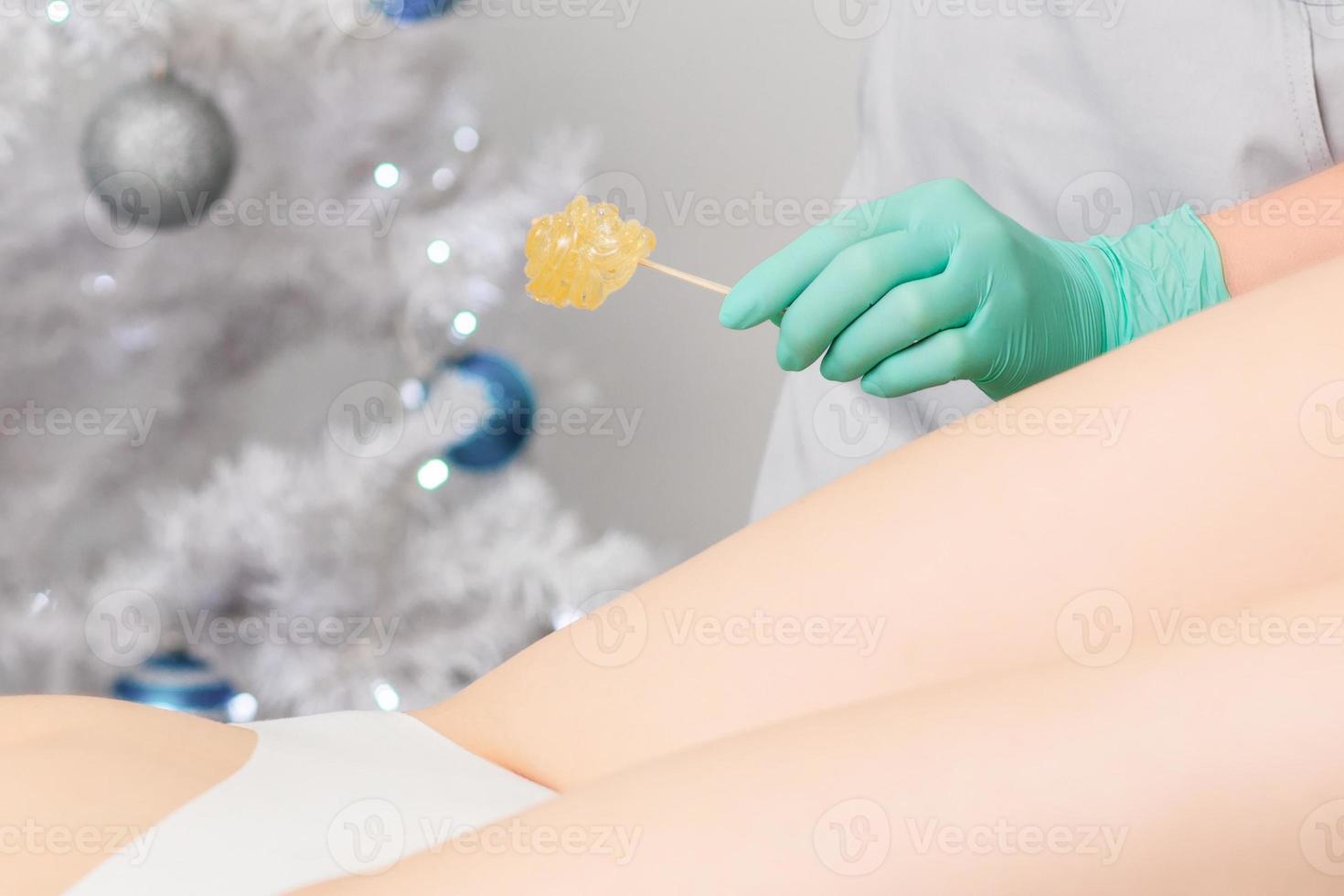 Young woman getting wax epilation of legs photo