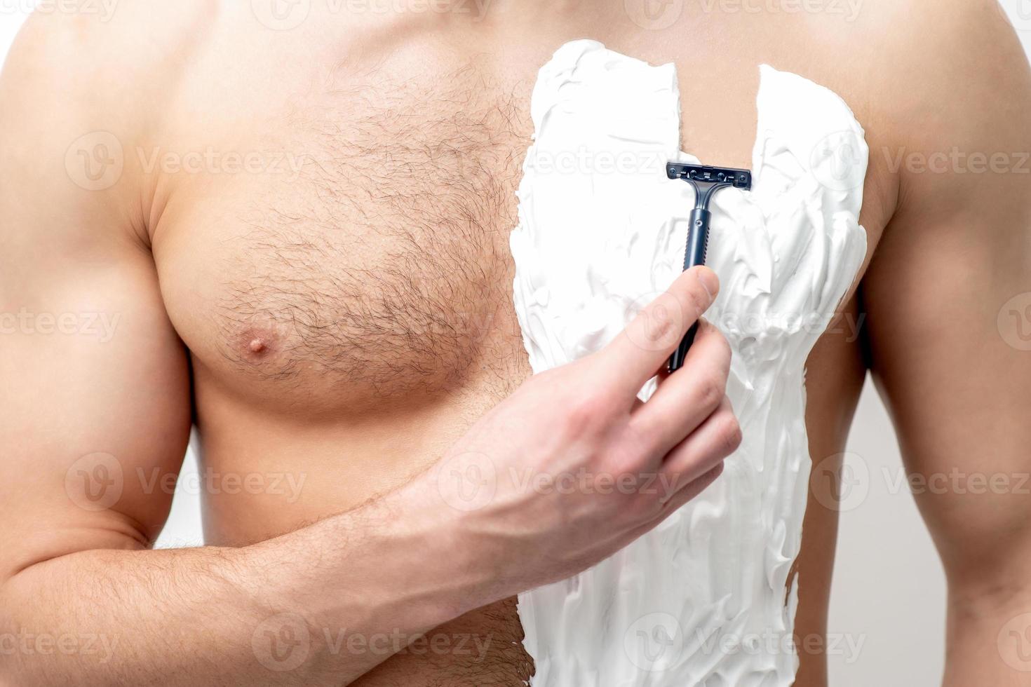 Young man shaving his chest photo