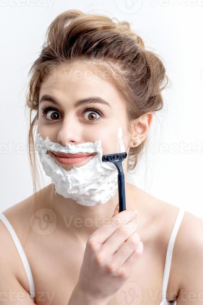 Woman shaving her face by razor photo