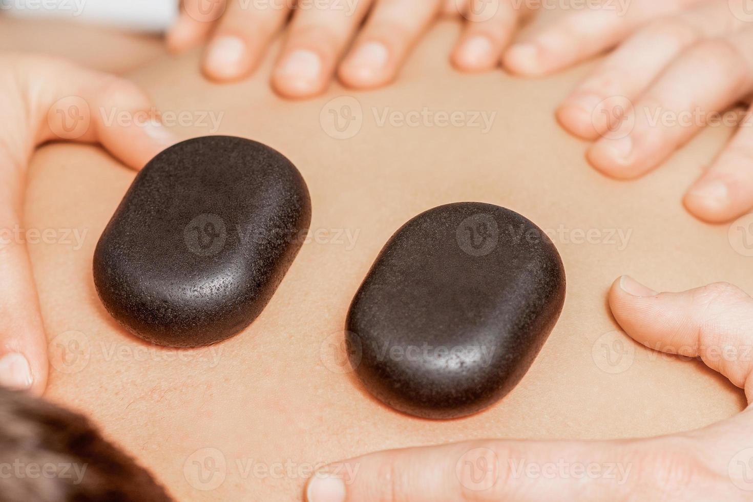 Stone massage on back of man. photo