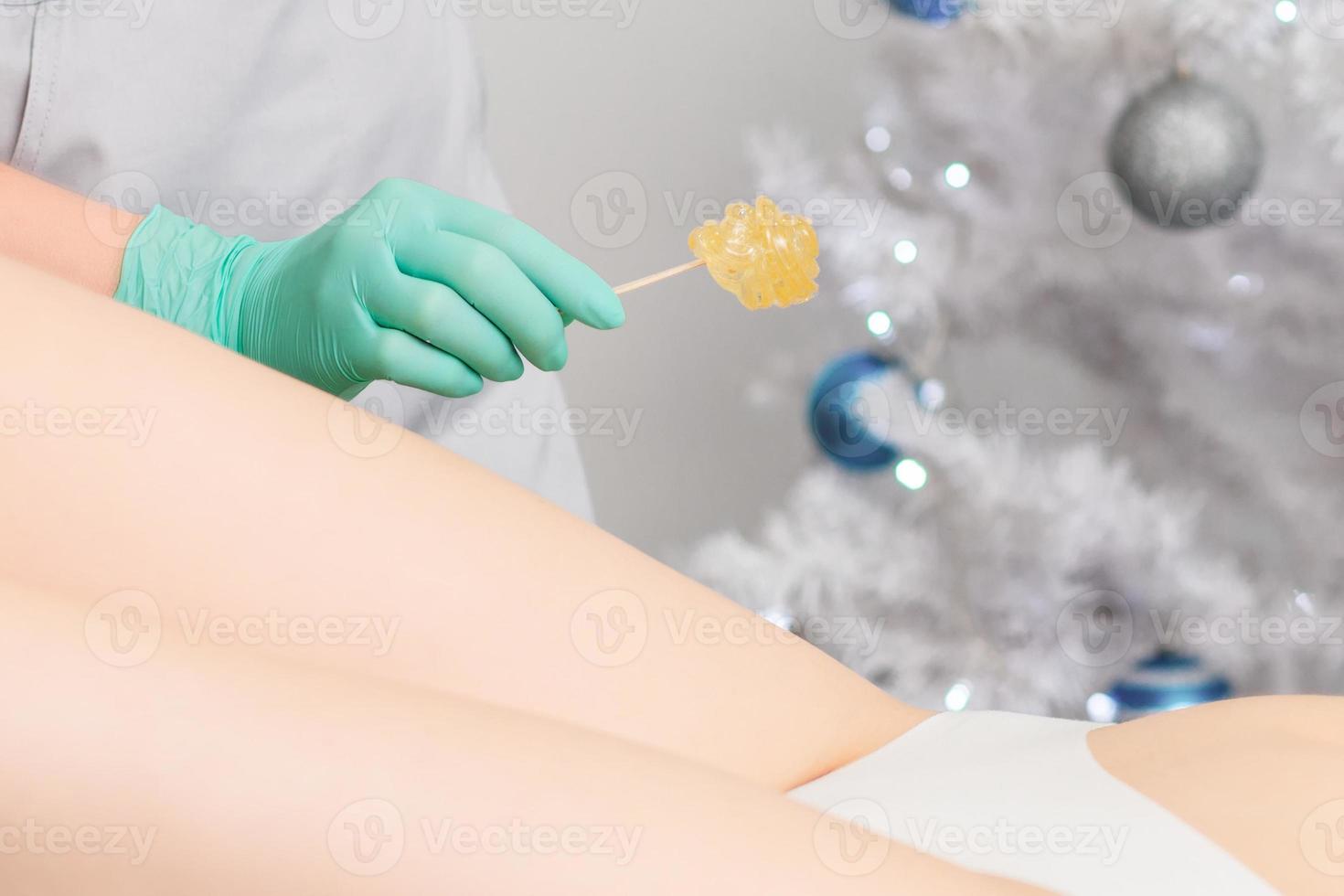 Young woman getting wax epilation of legs photo