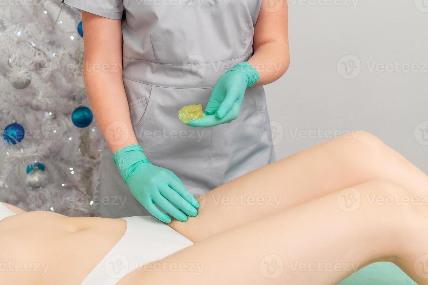 Cosmetologist in gloves applying paste for sugaring depilation photo