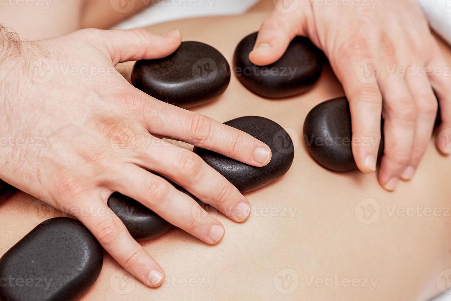 Stone massage on back of man. photo