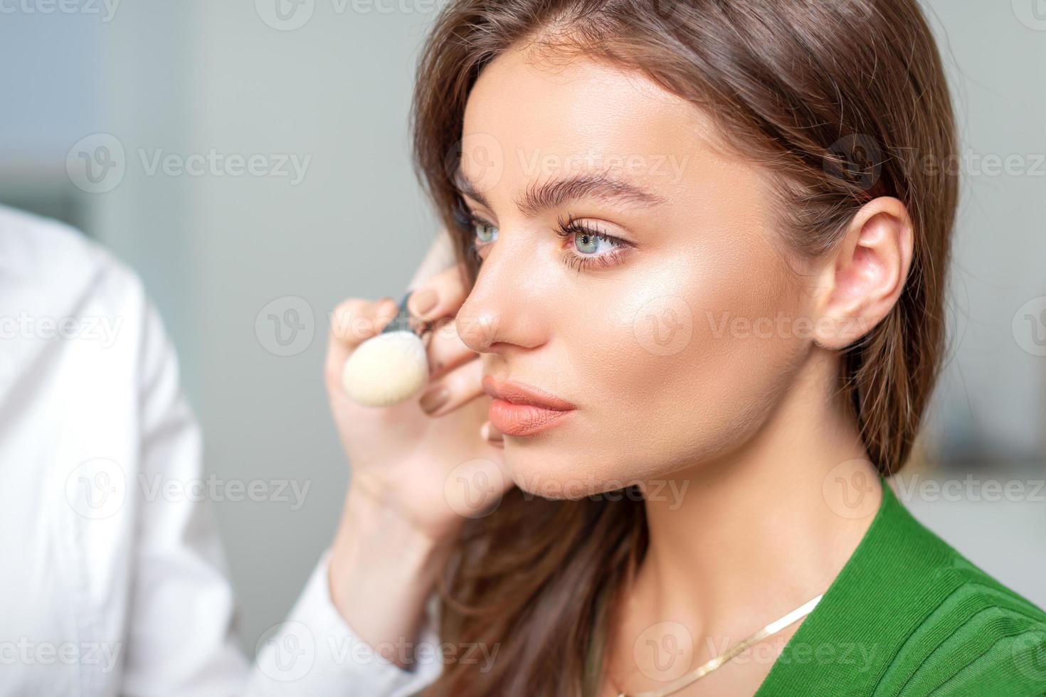 Makeup artist applying dry cosmetic tonal foundation photo