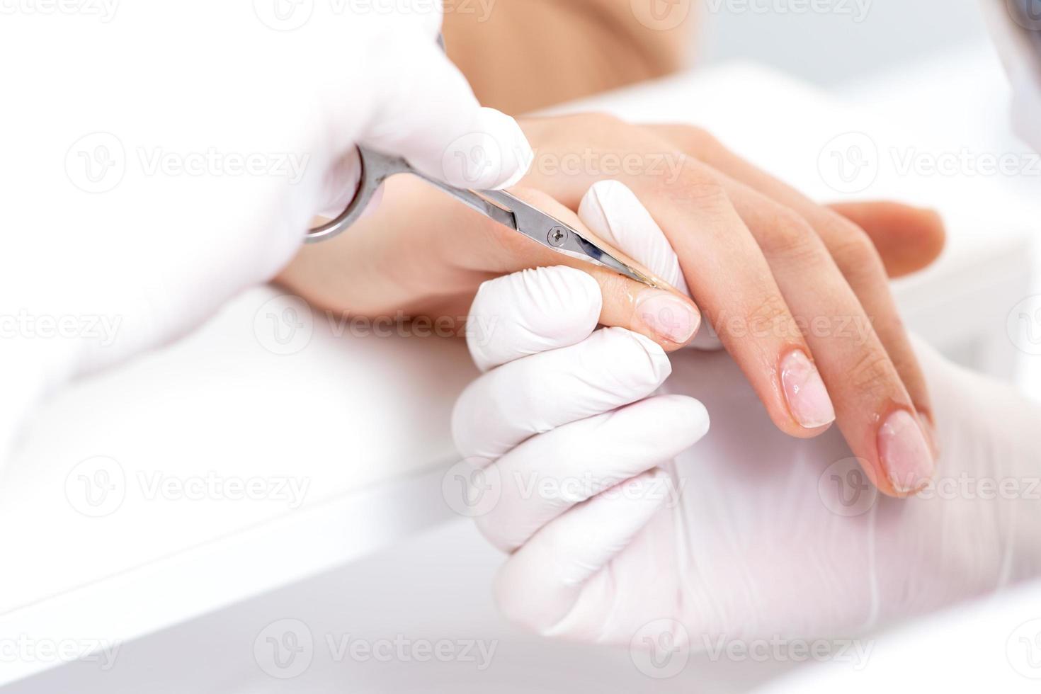 Close up of manicurist using manicure scissors photo
