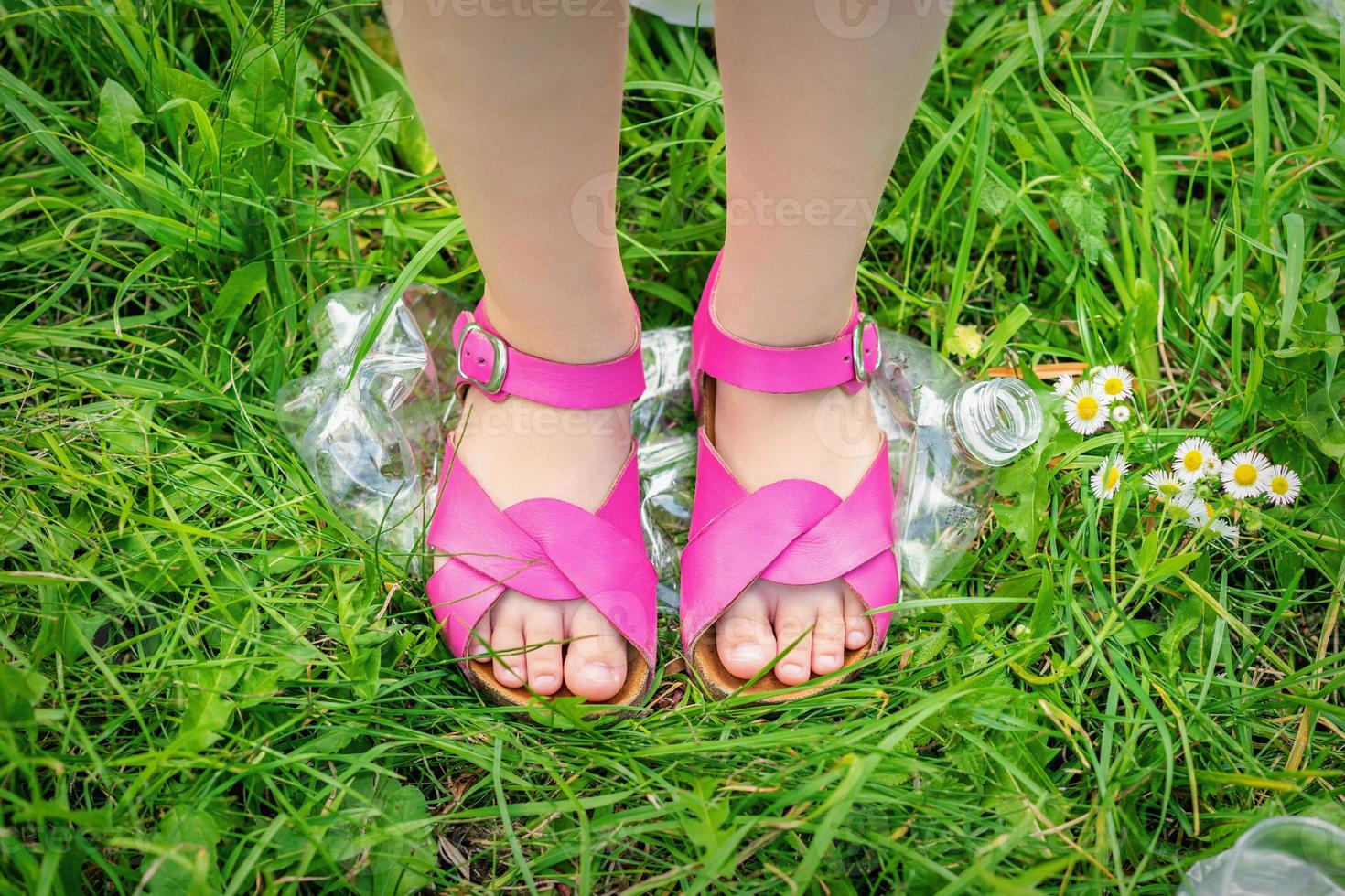 Legs of a little girl tramples a plastic bottle photo