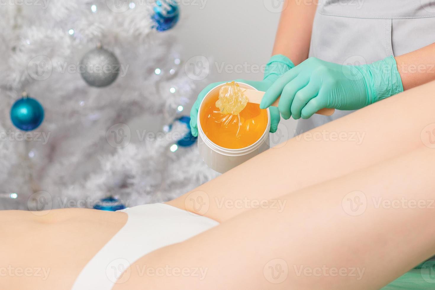 Young woman getting wax epilation of legs photo