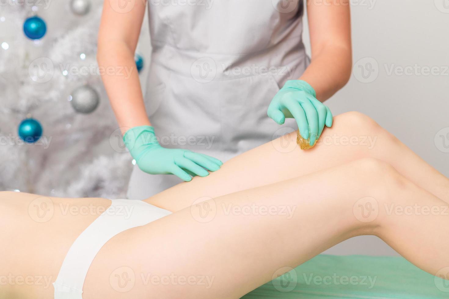 Beautician waxing legs of woman. photo