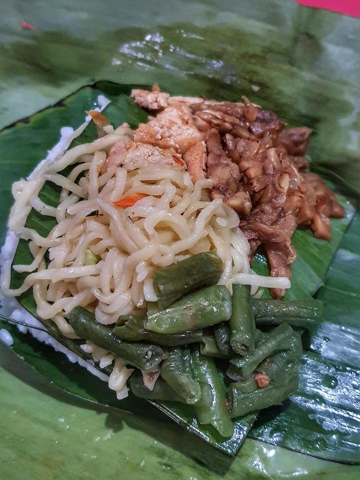 Nasi Kucing, food with small portions typical of Central Java. Contains rice, stir-fried vegetables, usually chickpeas, stir-fried tempeh, soy sauce, and fried noodles. photo