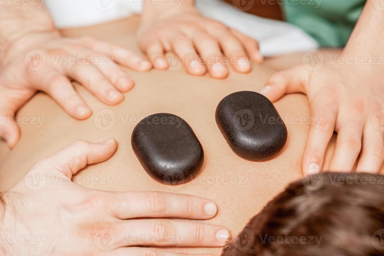 Stone massage on back of man. photo