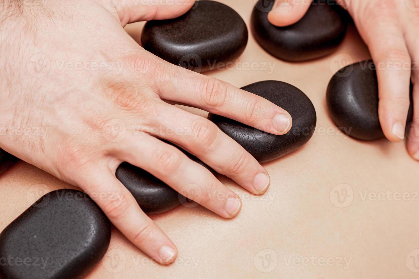 Stone massage on back of man. photo
