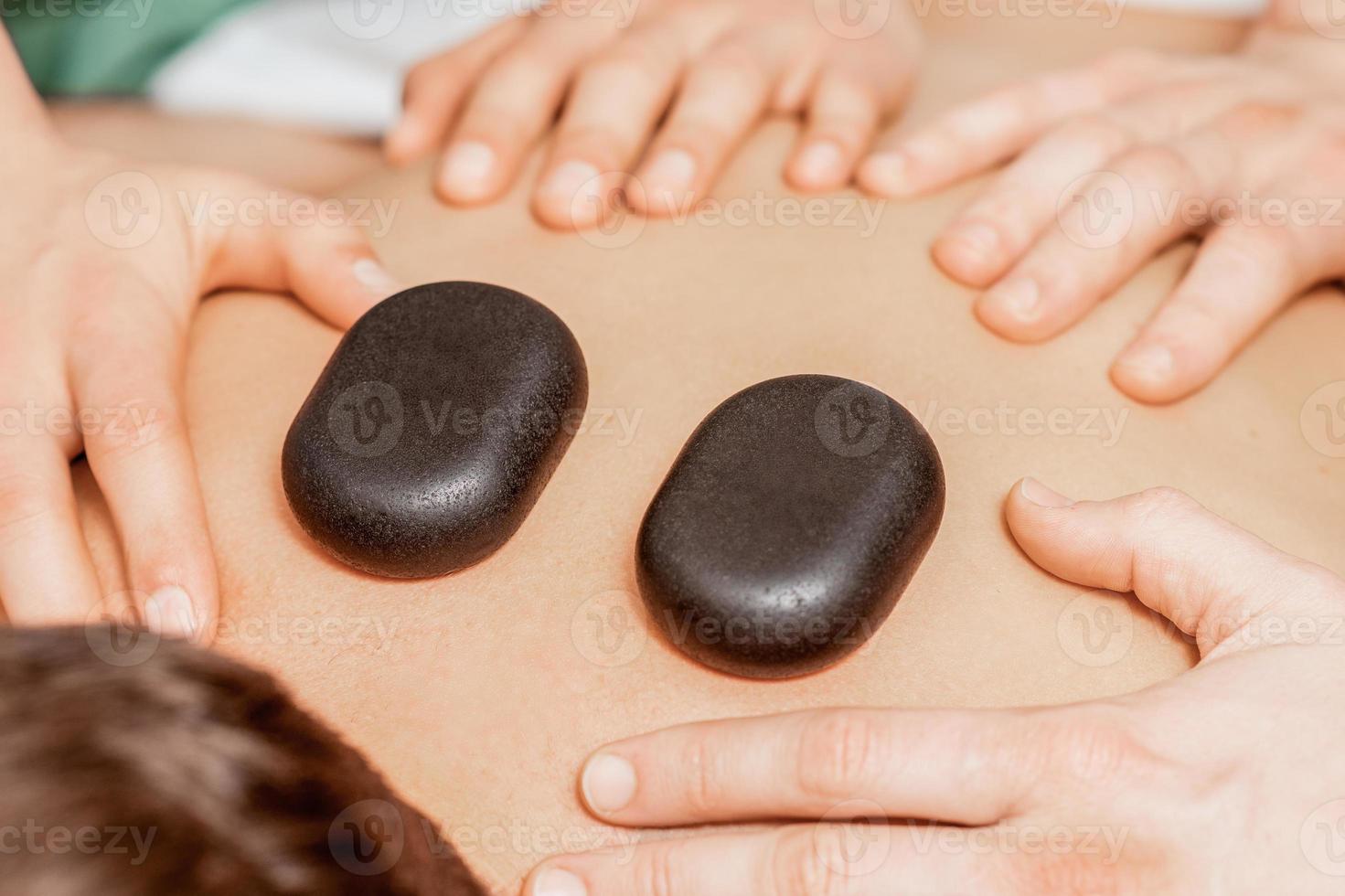 Stone massage on back of man. photo