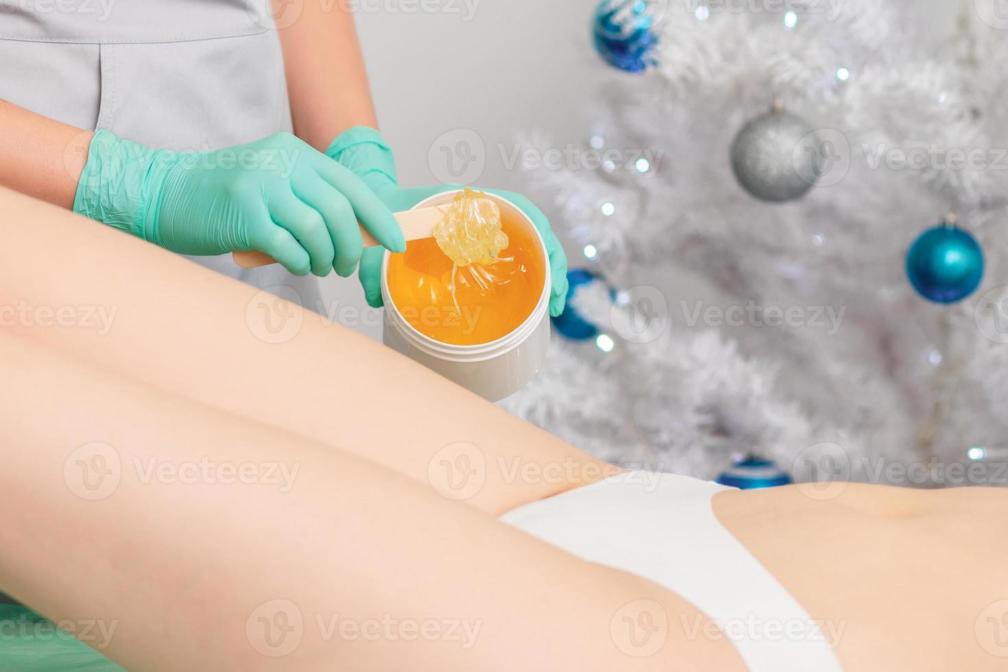 Young woman getting wax epilation of legs photo
