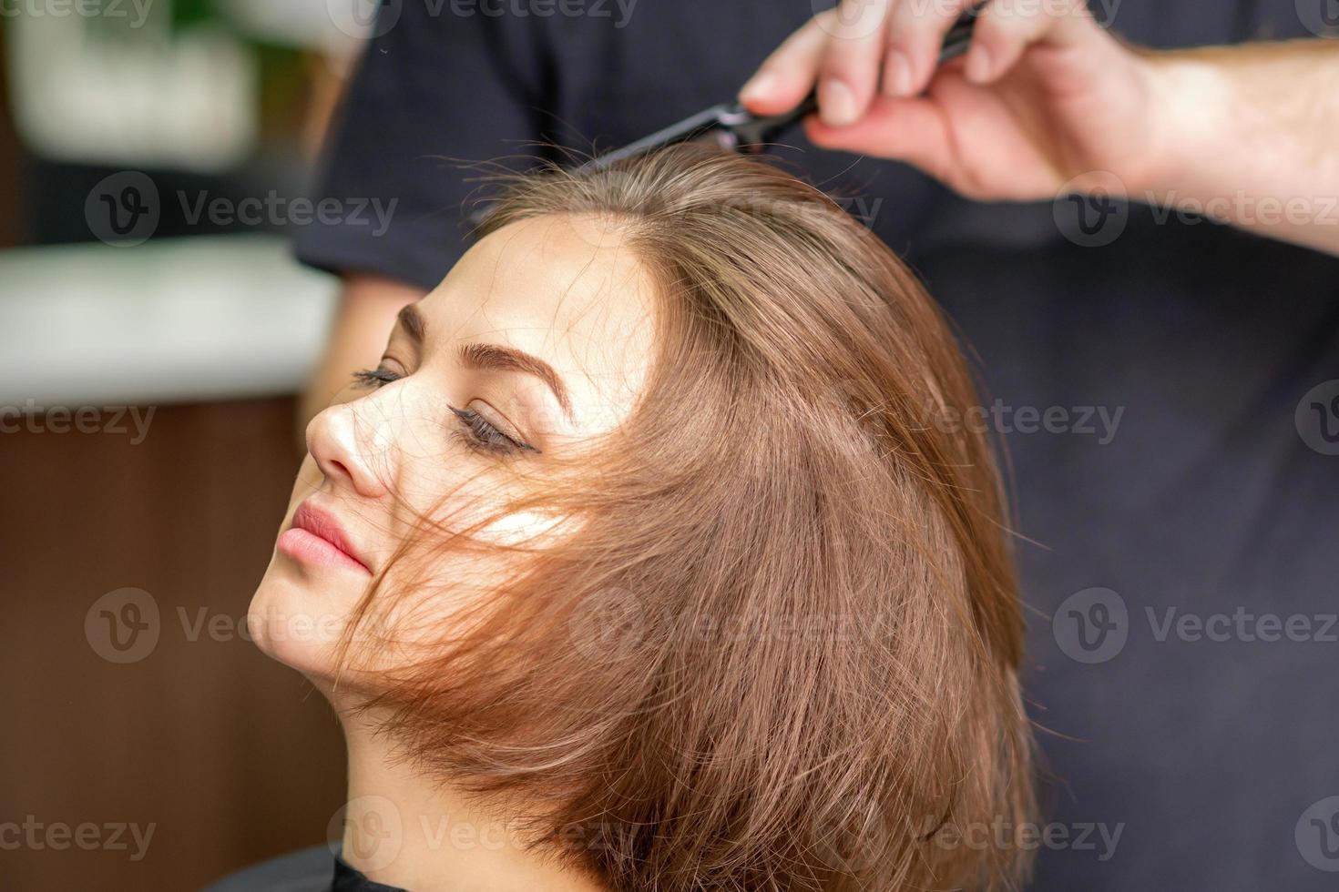 Hand of hairdresser combs hair of young woman photo