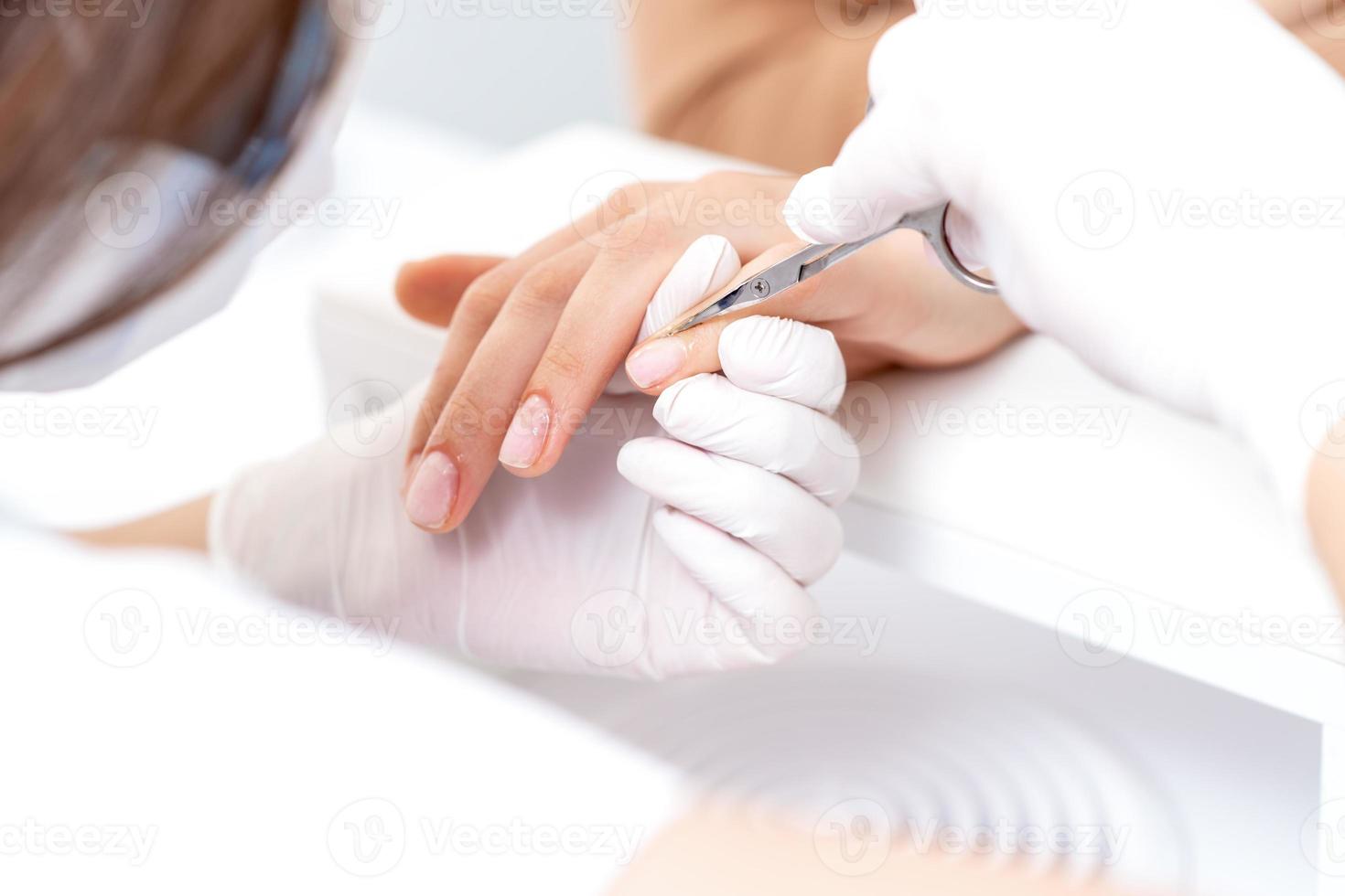 Close up of manicurist using manicure scissors photo