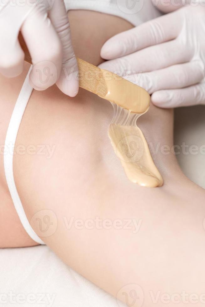 Cosmetologist applying wax paste on armpit photo