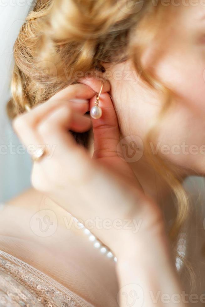 Bride dresses earrings before wedding photo