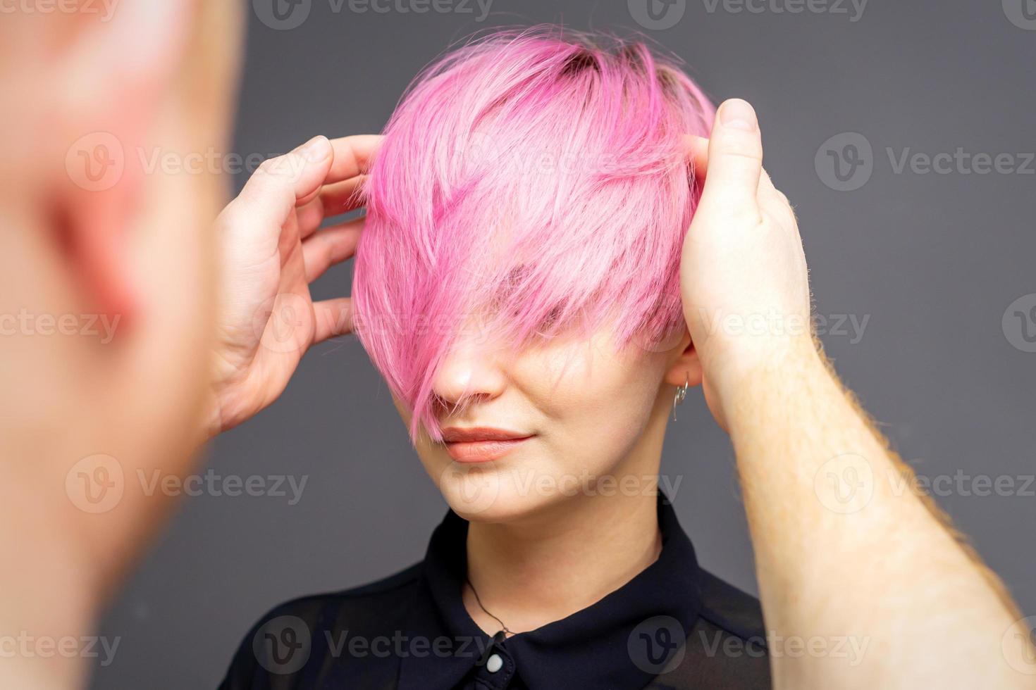 Hairdresser checking woman's pink hairstyle. photo