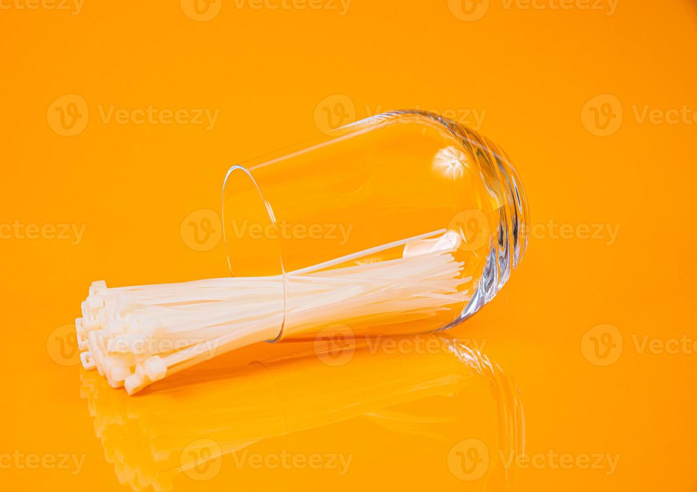nylon cable ties in glass in jar in bucket on orange background photo