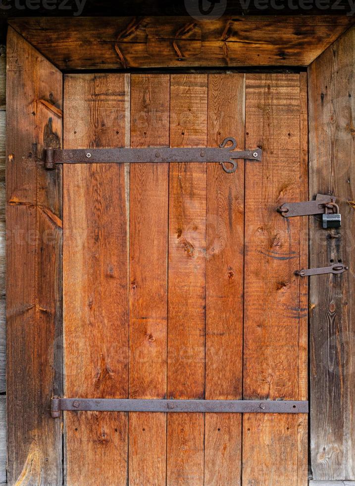 old weathered door in the wooden wall of an ancient hut photo