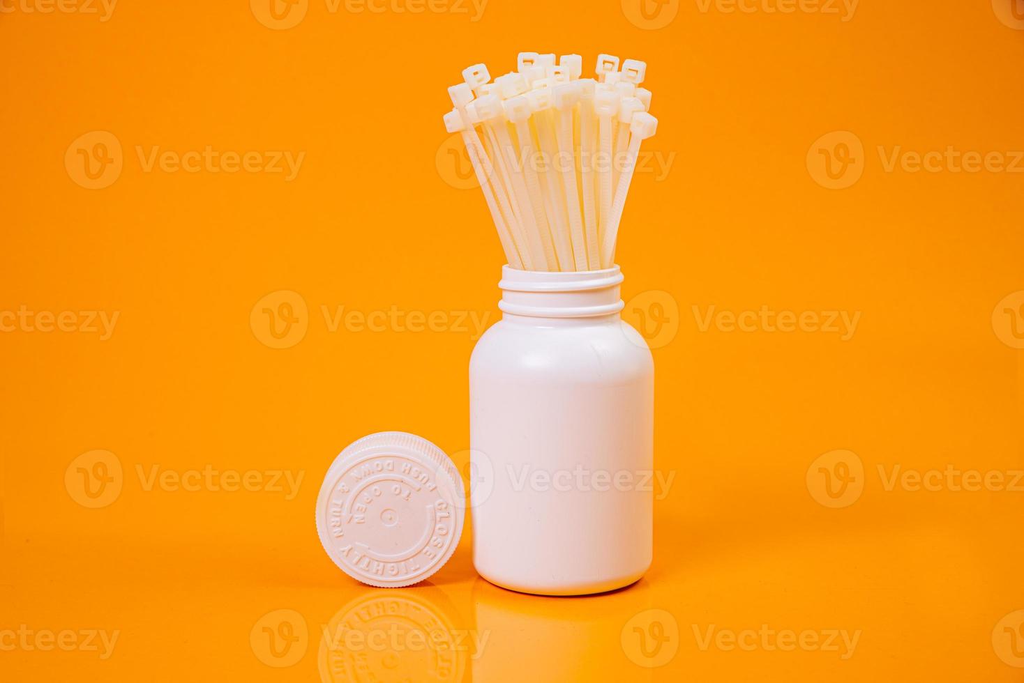 nylon cable ties in glass in jar in bucket on orange background photo