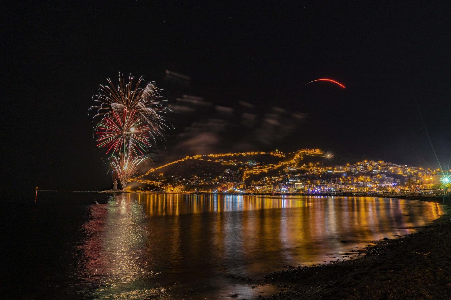 wonderful reflection of night fireworks on the sea and city sea view photo