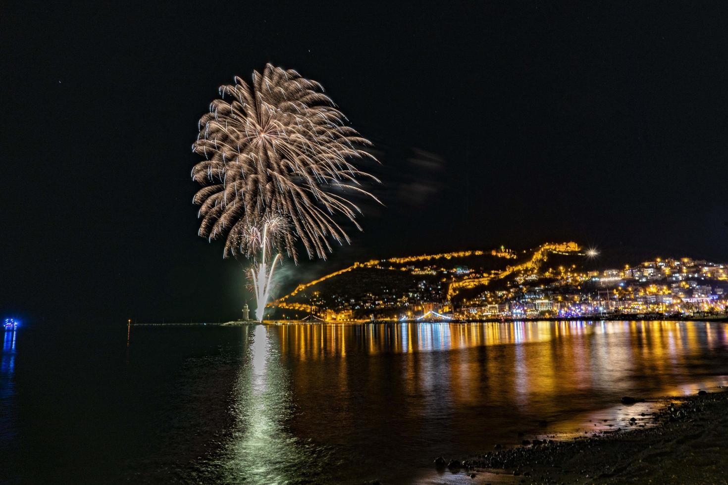 wonderful reflection of night fireworks on the sea and city sea view photo