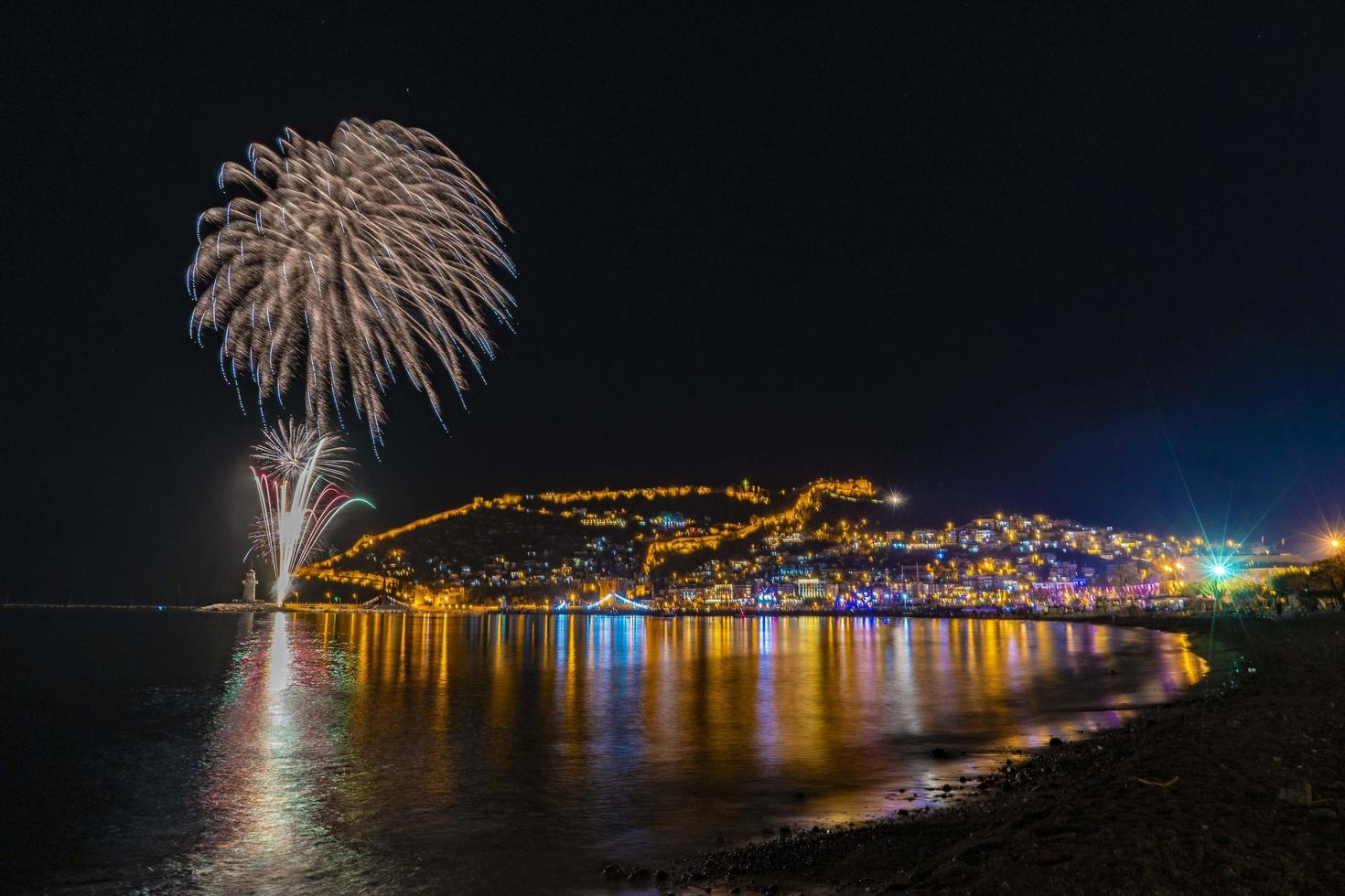 wonderful reflection of night fireworks on the sea and city sea view photo