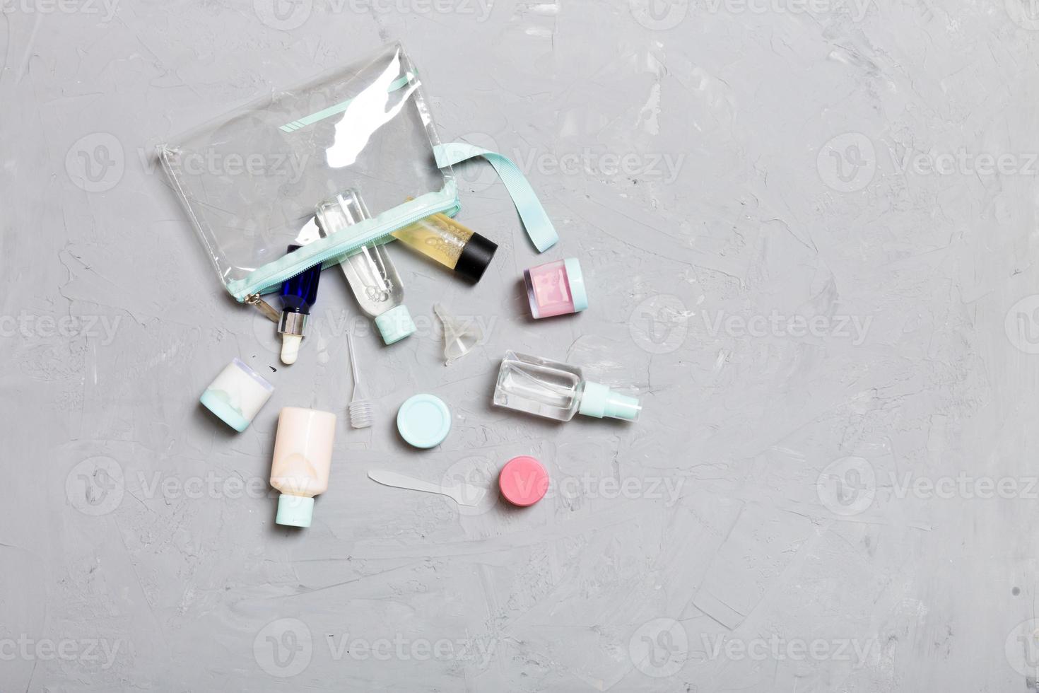 Top view of means for face care bottles and jars of tonic, micellar cleansing water, cream, cotton pads on gray background. Bodycare concept with empty cpace photo