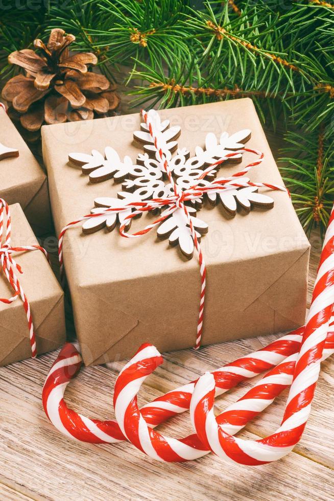 Fir tree branch with christmas gift box and candy canes on wooden background with copy space. Toned photo