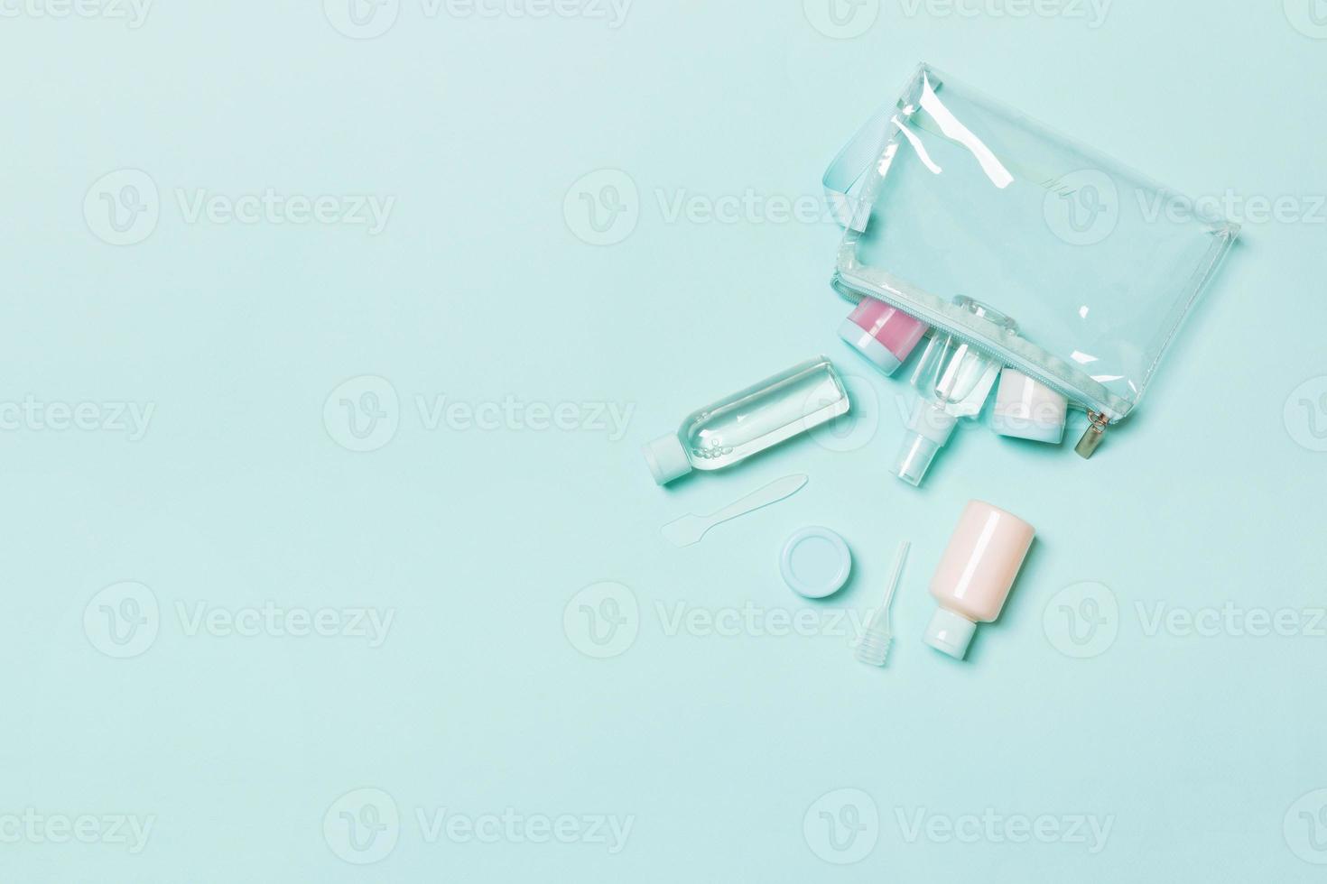 Top view of means for face care bottles and jars of tonic, micellar cleansing water, cream, cotton pads on blue background. Bodycare concept with empty cpace for your ideas photo