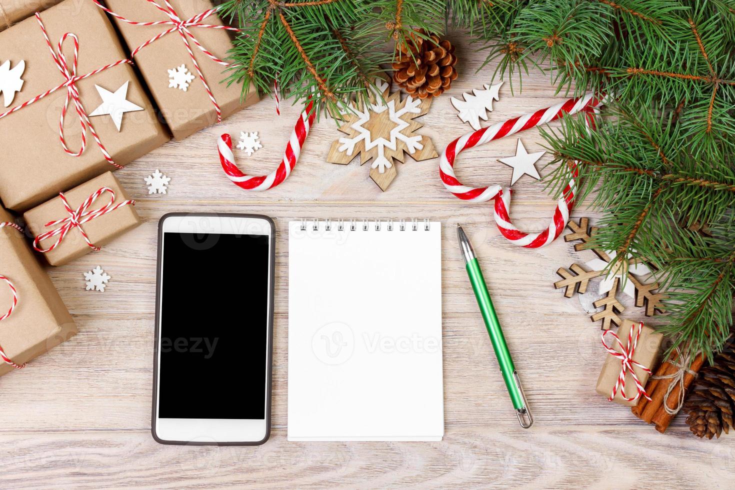 Christmas background with gift boxes, mobile phone with back screen and blank notebook, copy space. Template for new year goal or resolutions. Christmas mockup. Flat lay, top view photo