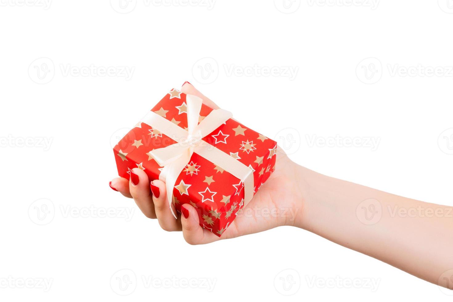 Woman hands give wrapped Christmas or other holiday handmade present in red paper with Gold ribbon. Isolated on white background, top view. thanksgiving Gift box concept photo