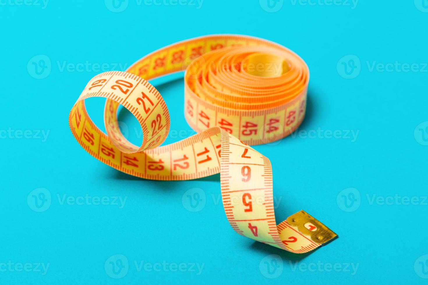 Close up of tangled measuring tape on blue background. Fitness and healthy diet concep with perspective view photo